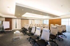 A conference room with rows of chairs, a whiteboard, and a small table. - Parkroyal Suites Bangkok (Bangkok)