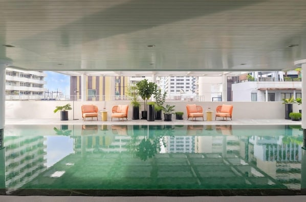 An indoor swimming pool with lounge chairs and potted plants.