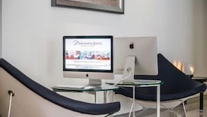 A room with a computer monitor displaying a webpage, a laptop, and two chairs. - Parkroyal Suites Bangkok (Bangkok)
