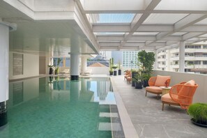 A rooftop pool area with lounge chairs and potted plants. - Parkroyal Suites Bangkok (Bangkok)