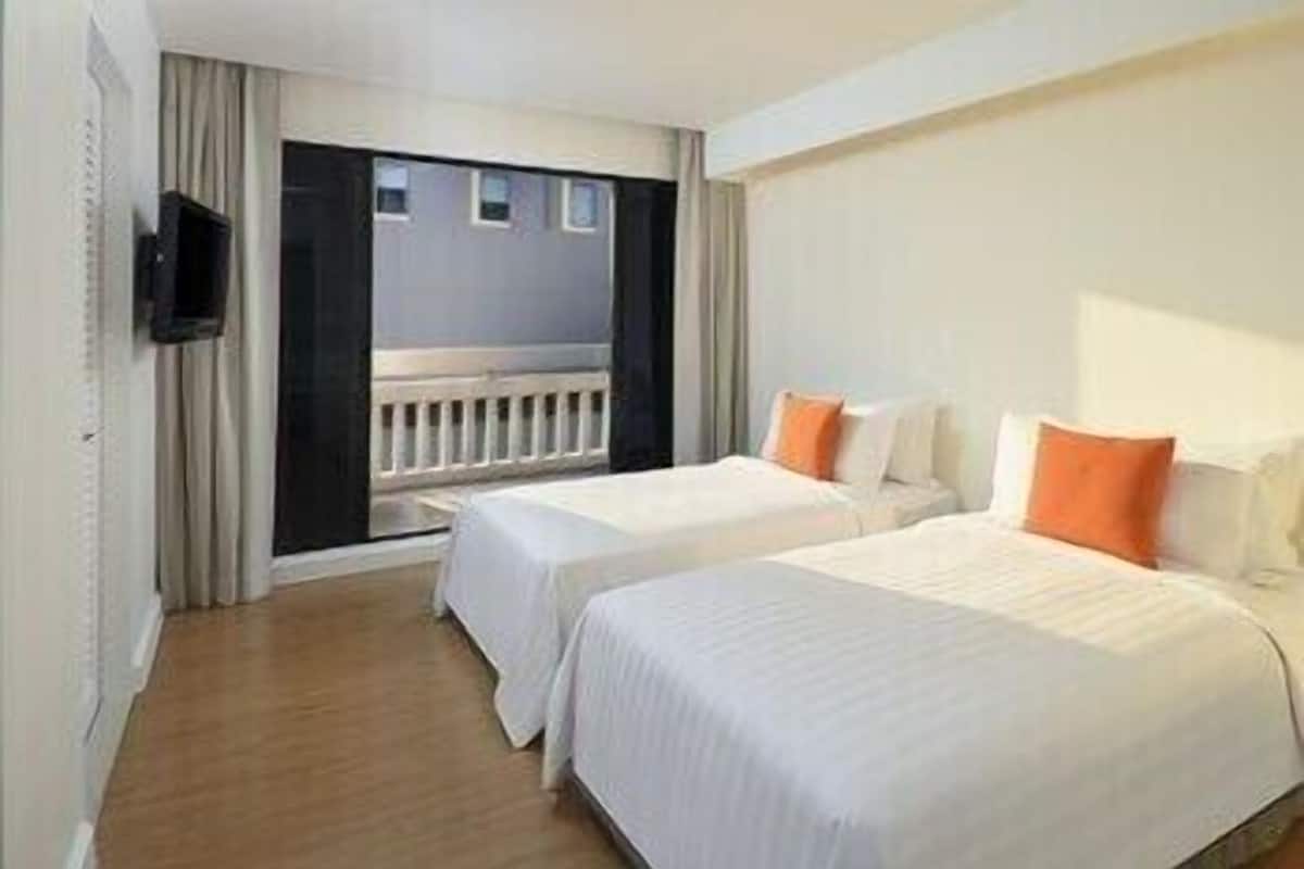 Ein Hotelzimmer mit zwei Betten, einem Fernseher und einem Balkon.