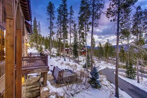 A wooden cabin with a balcony overlooking a snowy landscape and a winding road.