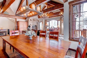 A spacious dining area with a wooden table, chairs, and a chandelier. - Rustic Timber Lodge (Breckenridge)