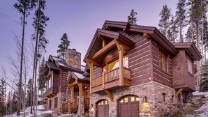 A log cabin with a stone foundation, wooden balconies, and a stone chimney. - Rustic Timber Lodge (Breckenridge)
