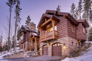 A log cabin with a stone foundation, wooden balconies, and a stone chimney. - Rustic Timber Lodge (Breckenridge)