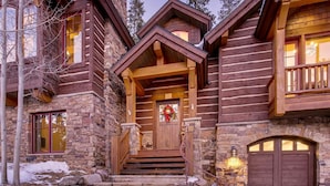 A log cabin with a stone facade, a wooden front porch, and a stone fireplace. - Rustic Timber Lodge (Breckenridge)