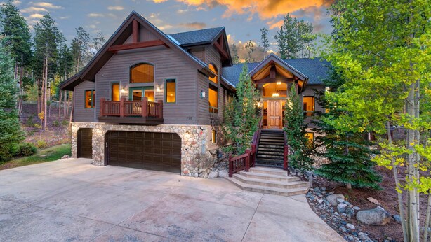A two-story house with a stone foundation, a garage, and a staircase leading to the second floor. - Inglenook (Breckenridge)
