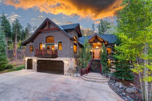 A two-story house with a stone foundation, a garage, and a staircase leading to the second floor. - Inglenook (Breckenridge)