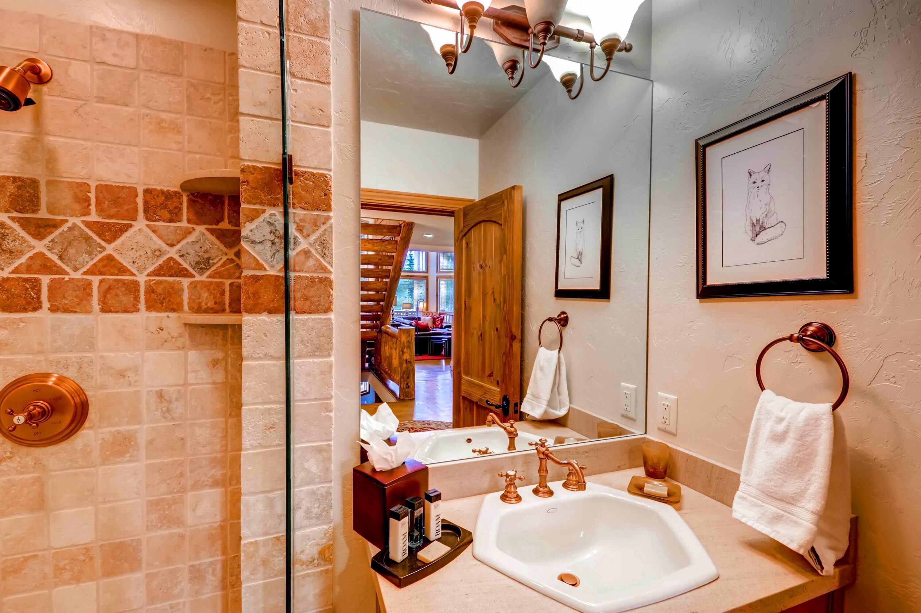 A bathroom with a large mirror, a sink, and a shower area.