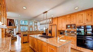 A spacious kitchen with wooden cabinets, granite countertops, and a large island. - Inglenook (Breckenridge)