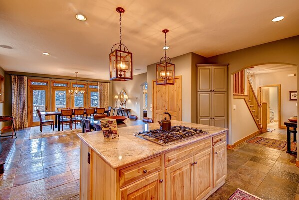 A spacious kitchen with a large island, wooden cabinets, and pendant lighting.