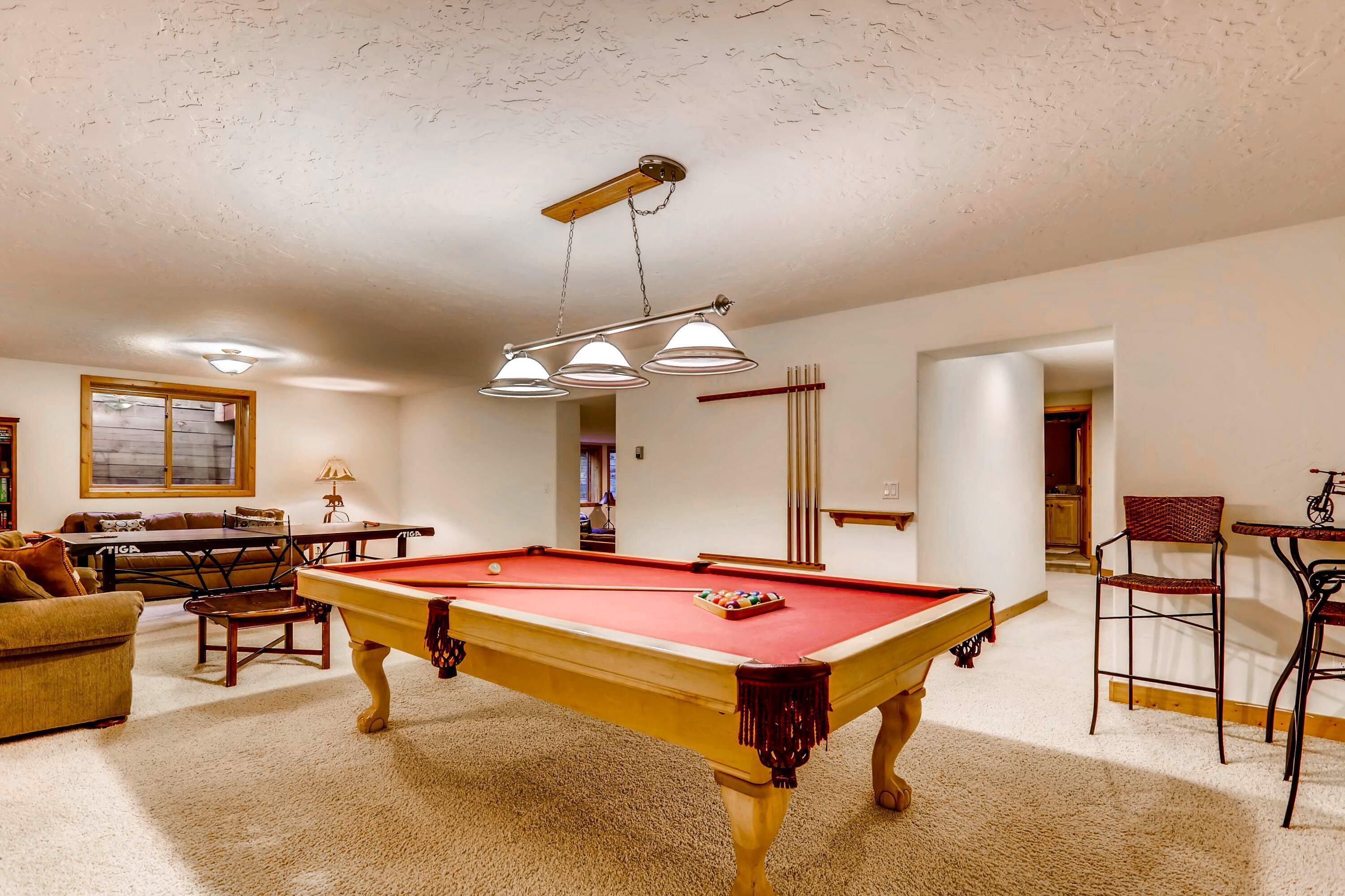 A pool table in a room with a ceiling fan, a window, and a door leading to another room.