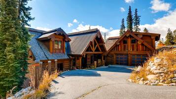 A log cabin with a garage, surrounded by trees and a clear sky.
