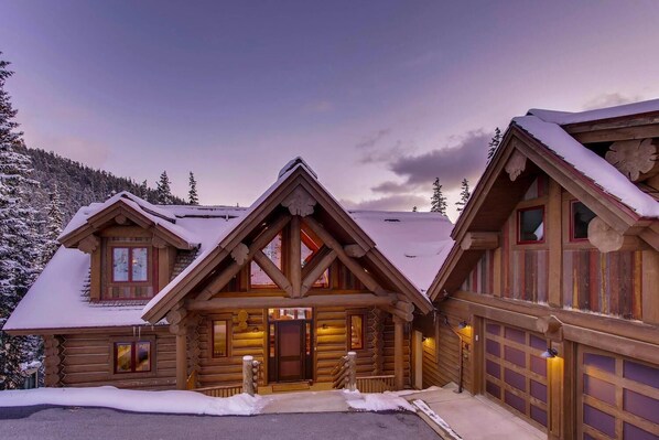 A log cabin with a central entrance, multiple windows, and a garage.