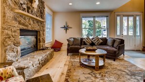 A cozy living room with a stone fireplace, a leather sofa, and a coffee table. - Hideaway on High (Breckenridge)