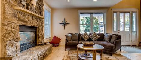 A cozy living room with a stone fireplace, a leather sofa, and a coffee table.