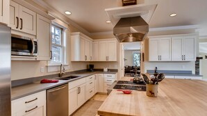 A modern kitchen with white cabinetry, stainless steel appliances, and a wooden island with utensils. - Hideaway on High (Breckenridge)