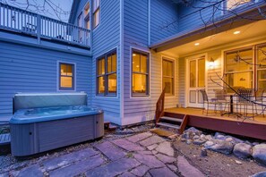 Une maison avec un jacuzzi, un chemin en pierre et une terrasse avec des chaises.