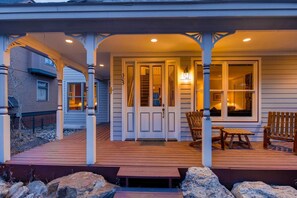 A covered porch with a wooden deck, a bench, and a table. - Hideaway on High (Breckenridge)