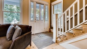 A living room with a brown leather sofa, a white door, and a wooden staircase. - Hideaway on High (Breckenridge)