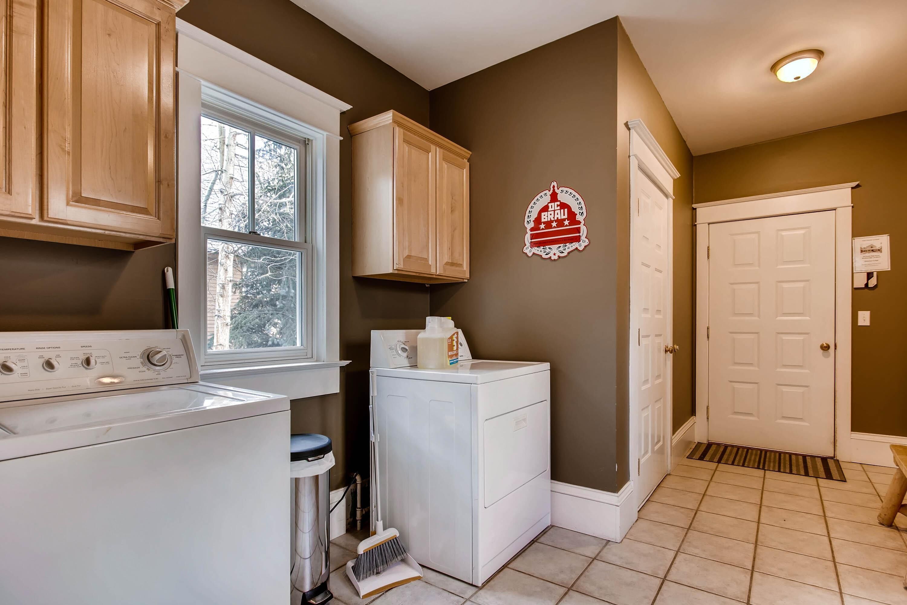 A laundry room with a washing machine, dryer, and wooden cabinets.