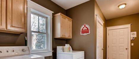 A laundry room with a washing machine, dryer, and wooden cabinets.