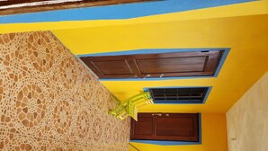 Eine Treppe mit gelb-blauer Farbgebung, eine Holztür und ein Fenster mit einem braunen Rollo.