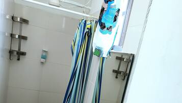 Ein Badezimmer mit Dusche, Waschbecken, Spiegel und Handtuchhalter.
