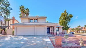 A two-story house with a garage, a front porch, and a small brick area with a fire hydrant. - Welcome to your Dream Home, up to 12 guests! (Henderson)