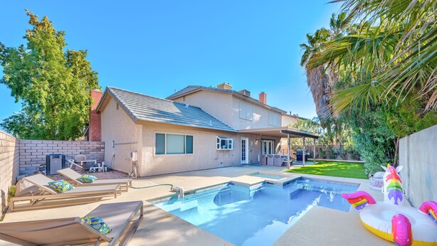 A backyard with a swimming pool, lounge chairs, and a house. - Welcome to your Dream Home, up to 12 guests! (Henderson)