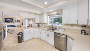 A spacious kitchen with white cabinets, a dishwasher, and a large window. - Welcome to your Dream Home, up to 12 guests! (Henderson)