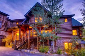 A log cabin with a stone foundation, wooden exterior, and a porch with stairs leading to a deck. - Ski Classic Lodge (Breckenridge)