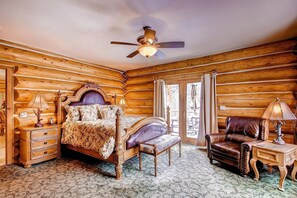 A log cabin-style bedroom with a four-poster bed, a leather armchair, a wooden nightstand, and a ceiling fan. - Ski Classic Lodge (Breckenridge)