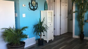 A hallway with a blue wall, wooden flooring, a white door, and a potted plant. - GREAT LAKEVIEW  LOCATION WITH TROPICAL VIBES (Lake Ozark)