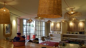 A spacious dining area with a long wooden table, wicker hanging lights, and a large woven basket. - Miostello Lifestyle Riad Marrakech (Marrakech)