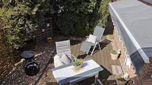 A patio with a table, chairs, a grill, and potted plants. - Ferienapartment Weber (Faßberg)