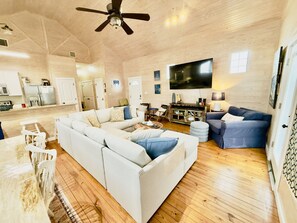 A spacious living area with a large sectional sofa, a television, and a wooden floor.