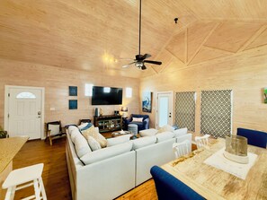 Un vaste espace de vie comprenant un grand canapé, une table à manger et un ventilateur de plafond.