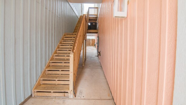 A narrow hallway with a wooden staircase leading to an upper level. - Private Hot Tub home + separate 1st floor studio (Port Aransas)