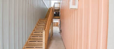 A narrow hallway with a wooden staircase leading to an upper level.