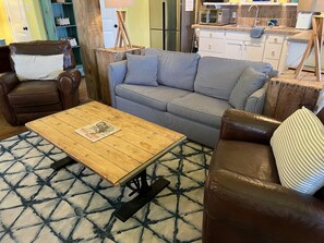 A living room with a brown leather sofa, a striped sofa, and a wooden coffee table. - Private Hot Tub home + separate 1st floor studio (Port Aransas)