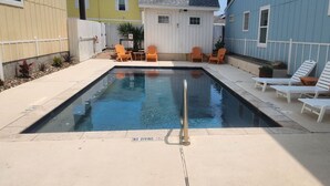 A rectangular swimming pool with a no diving sign, surrounded by lounge chairs and a small deck area. - Private Hot Tub home + separate 1st floor studio (Port Aransas)