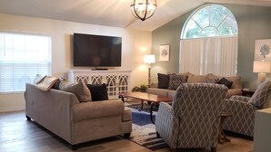 Una sala de estar con sofá, sillones, mesa de centro, televisor y chimenea.