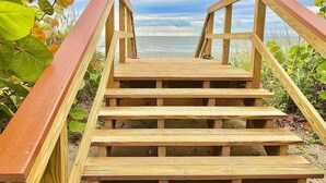 A wooden staircase leading to a beach with a view of the ocean.
