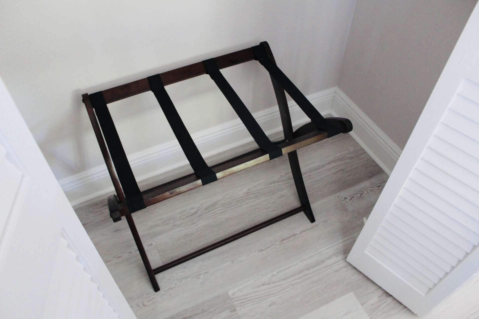 A corner of a room with a wooden bench against the wall, a white door, and a light-colored wooden floor.