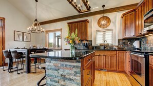 Une cuisine moderne avec des meubles en bois, un îlot central en pierre et un lustre.