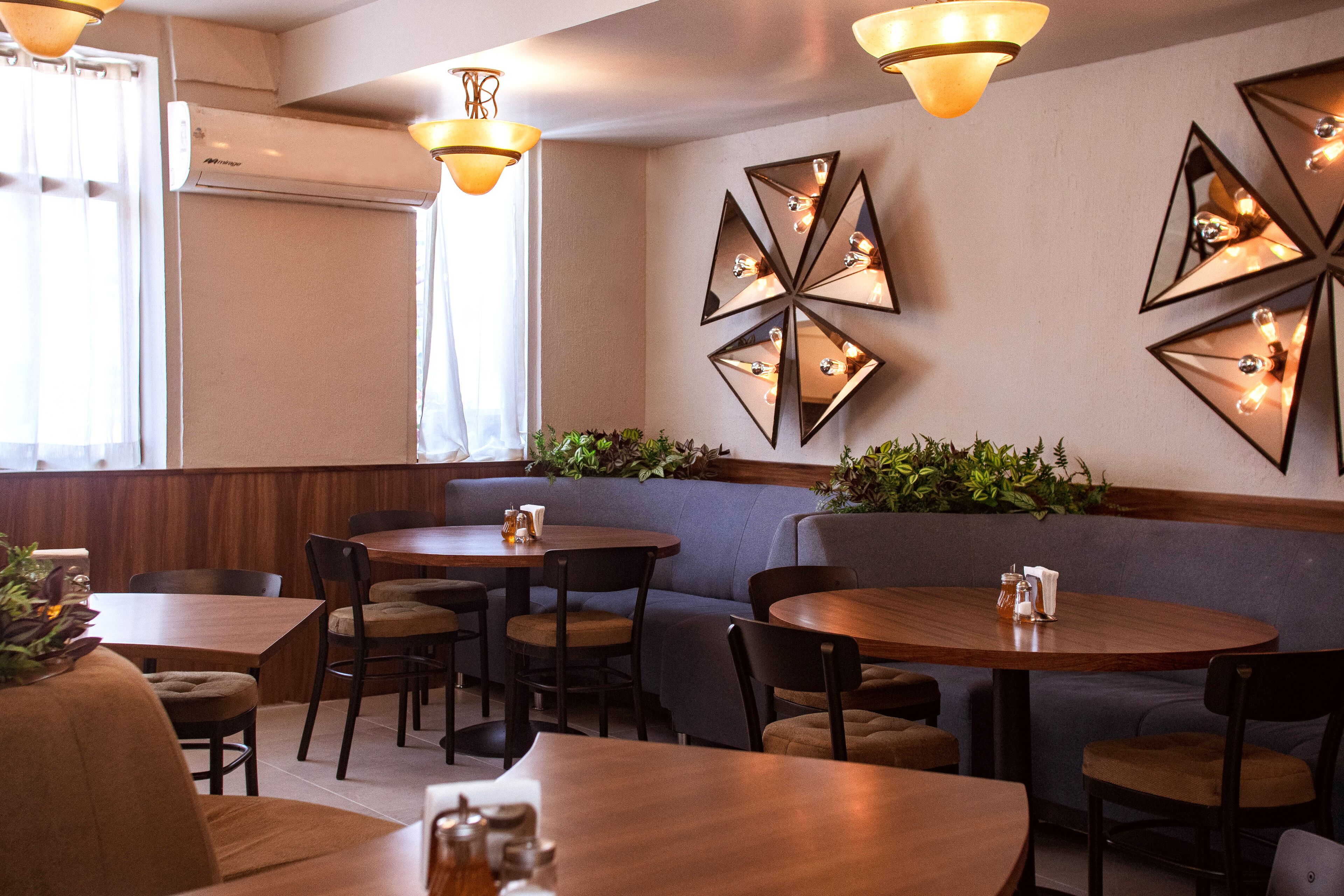 A restaurant with round tables, cushioned seating, and decorative wall mirrors.
