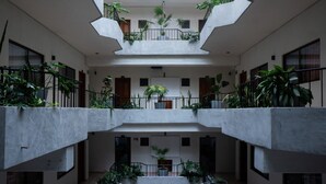 A multi-level atrium with concrete floors and railings, featuring potted plants and a central staircase. - Hotel Melanie Tepic (Tepic)