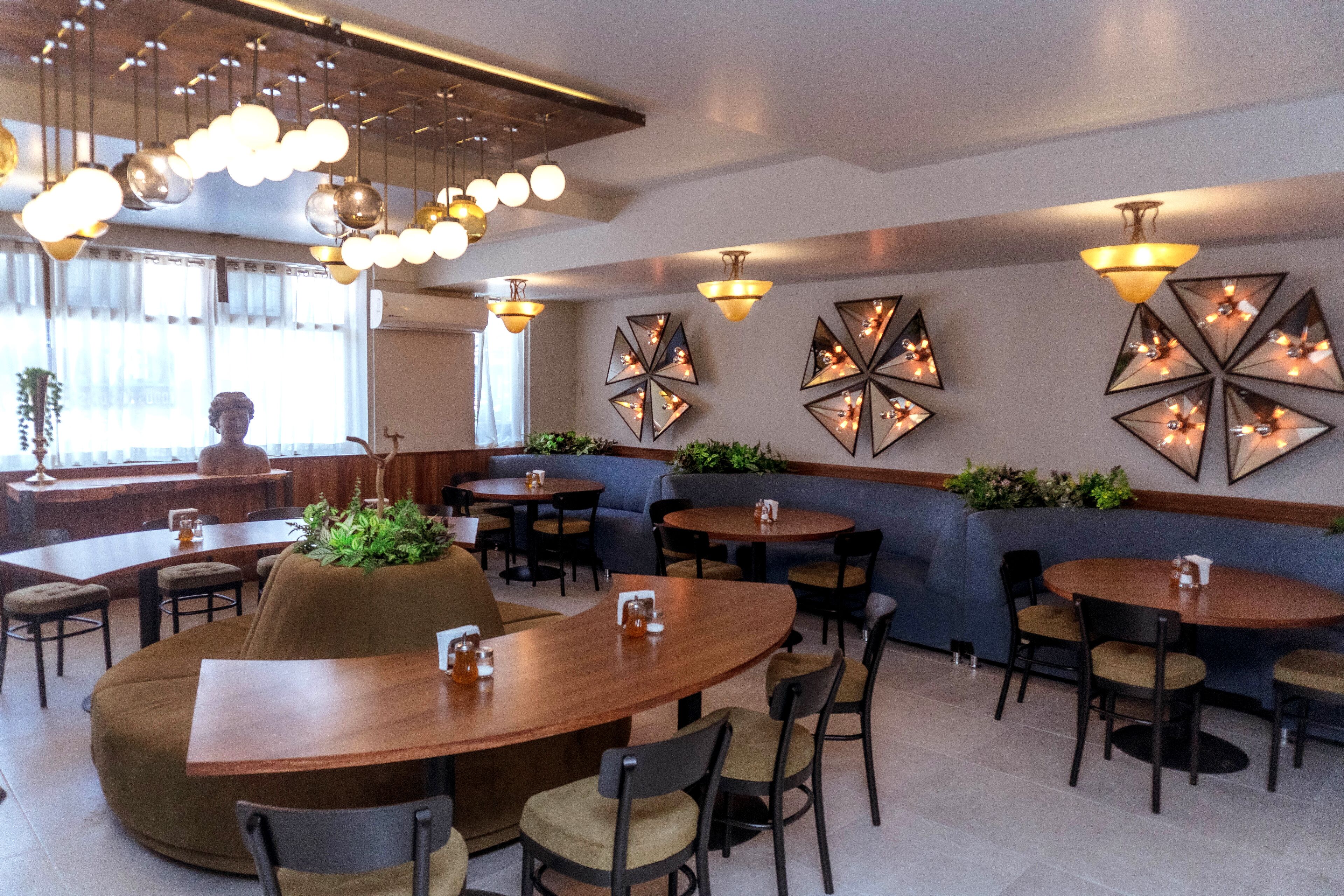 Ein modernes Restaurant mit runden Tischen, Sitzbänken und einer Bar.