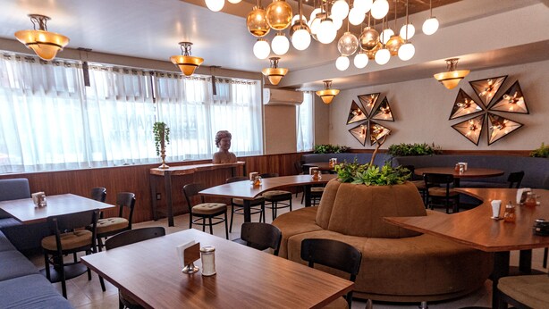 A restaurant interior with wooden tables, cushioned seating, and decorative wall art. - Hotel Melanie Tepic (Tepic)